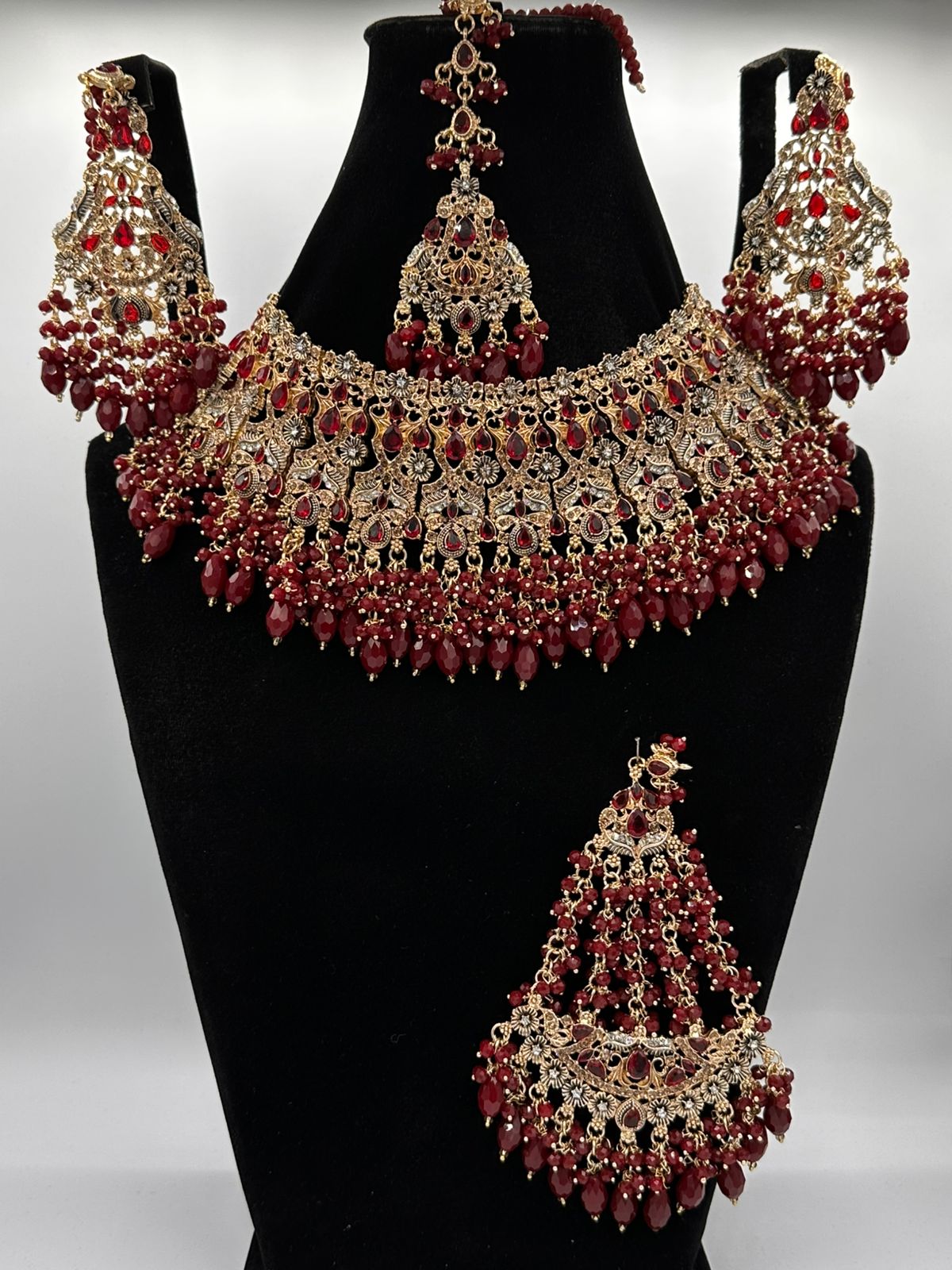 This is a maroon and goldplated bridal necklace and earring set